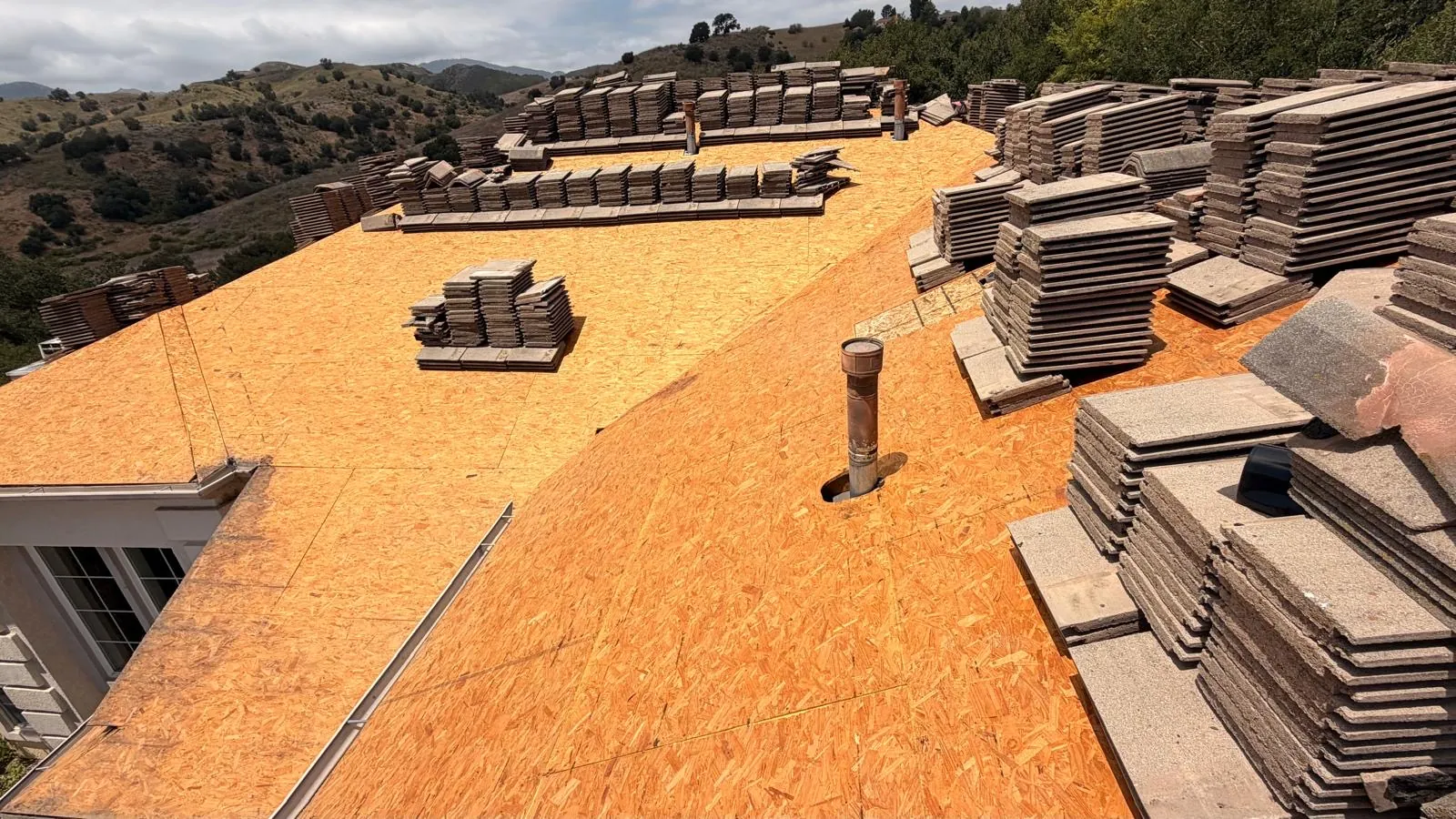 Removed concrete tiles stacked along the ridges while the Agoura Hills roof deck is open